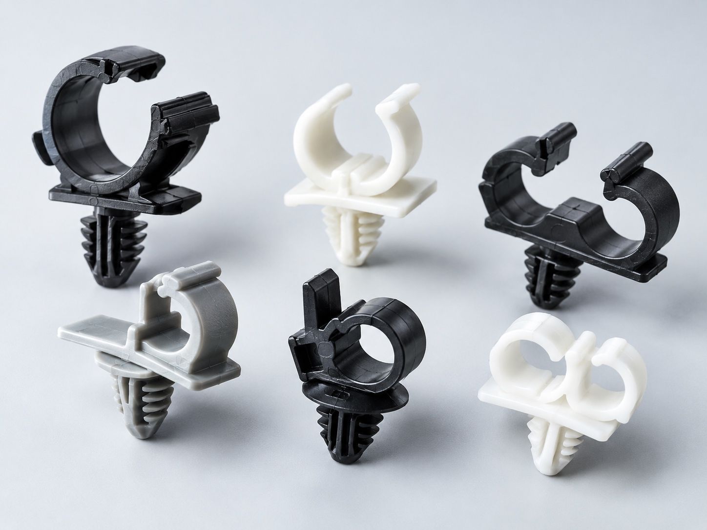 Assorted black and white plastic cable clips arranged on a white background