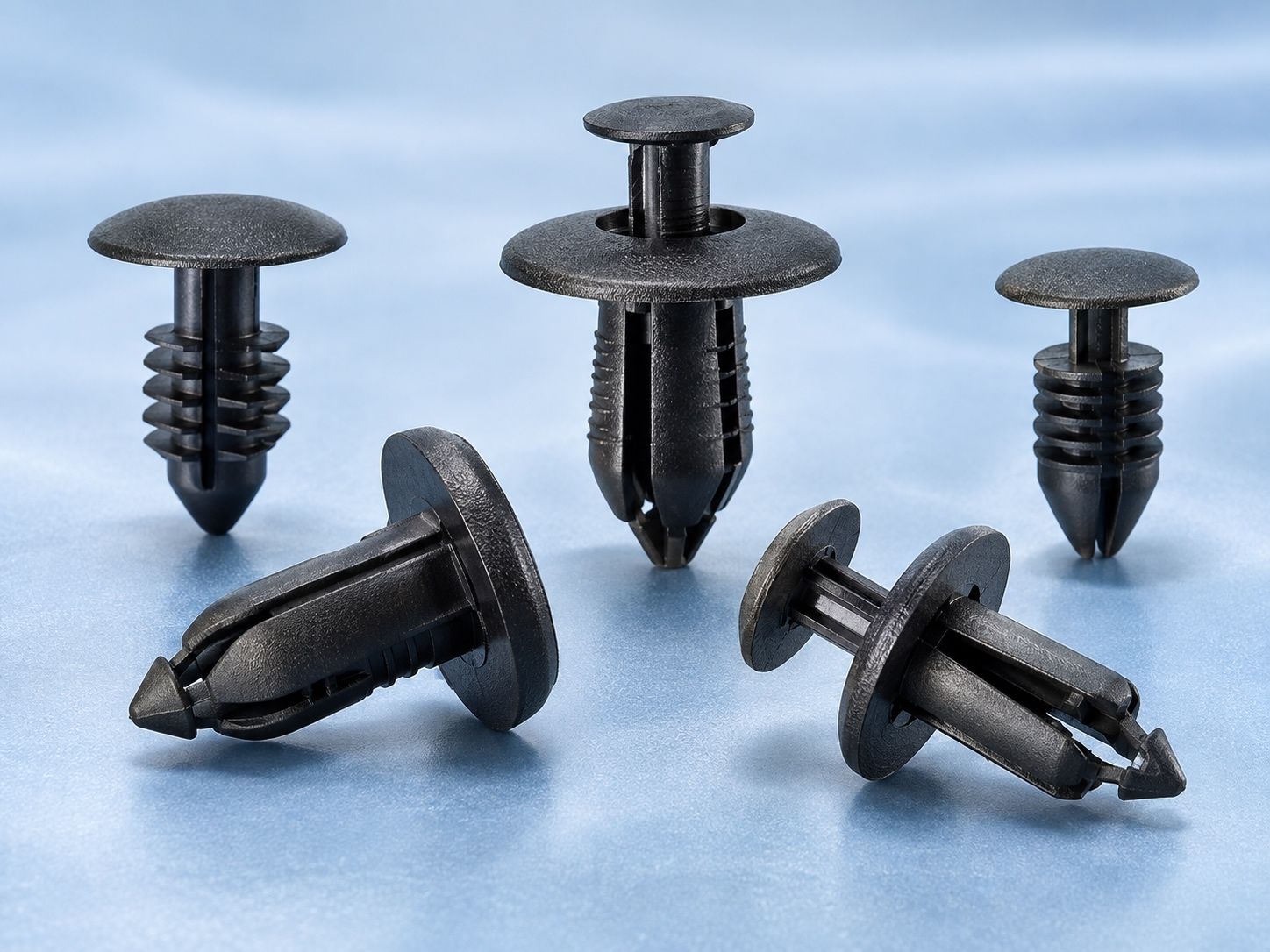 Black plastic push fasteners and clips arranged on a light blue background.