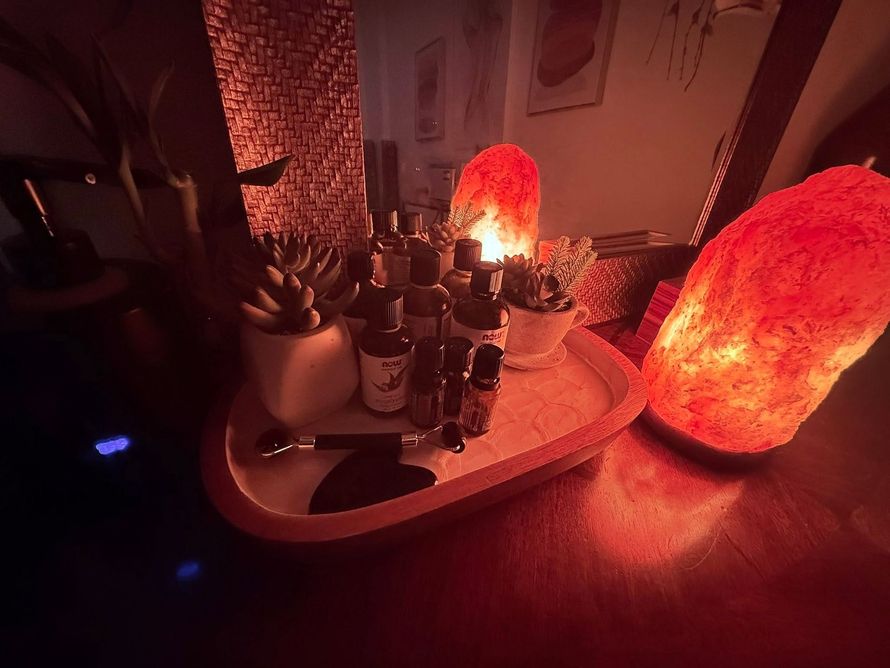 Red-lit tabletop with candles, bottles, and a glowing salt lamp in a dim room
