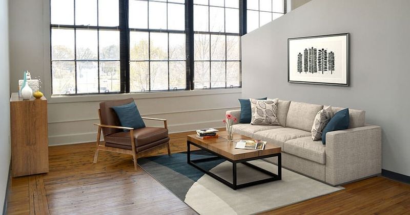 Modern living room with large windows, sofa, armchair, coffee table, and artwork.