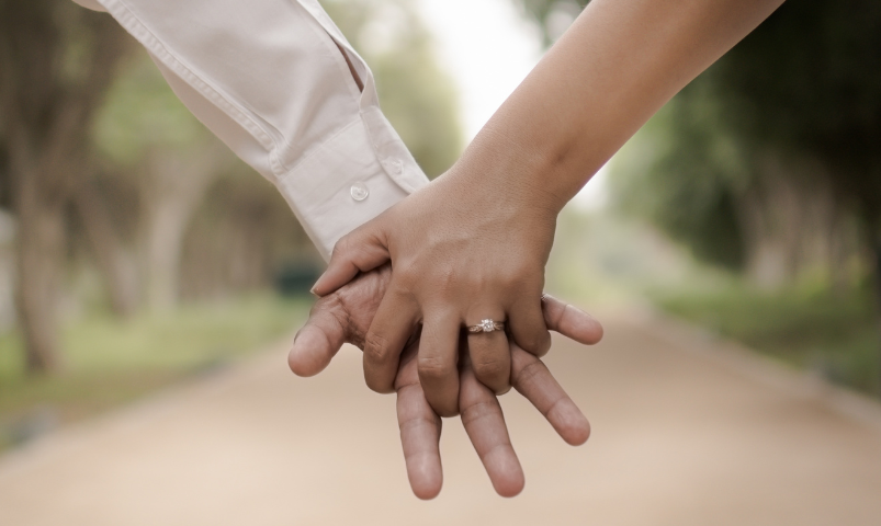 A man and a woman are holding hands with rings on their fingers.