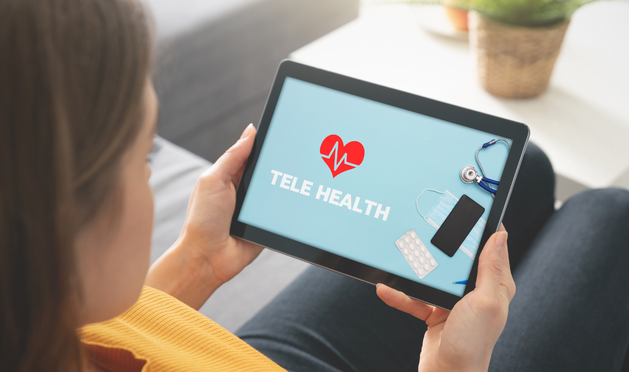 A woman is holding a tablet with tele health on the screen.