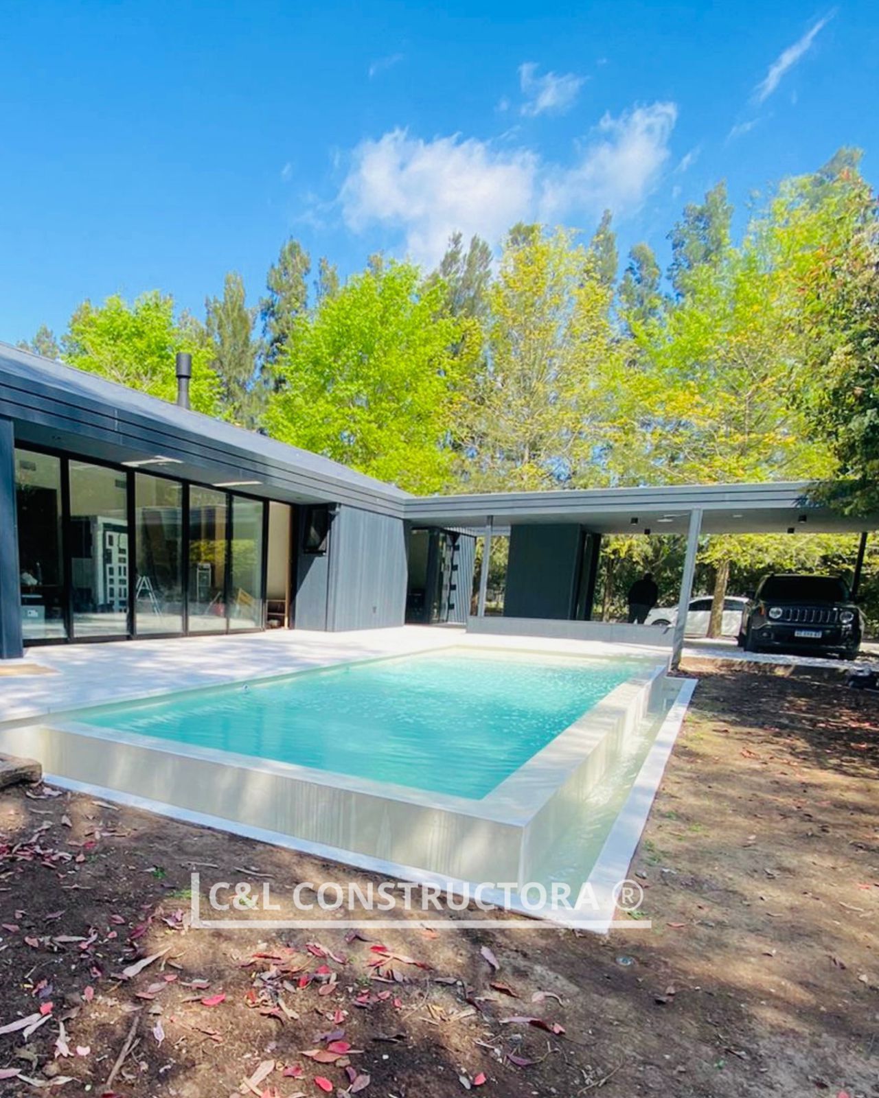 Piscina con jacuzzi y tumbonas en un patio trasero con una casa al fondo.