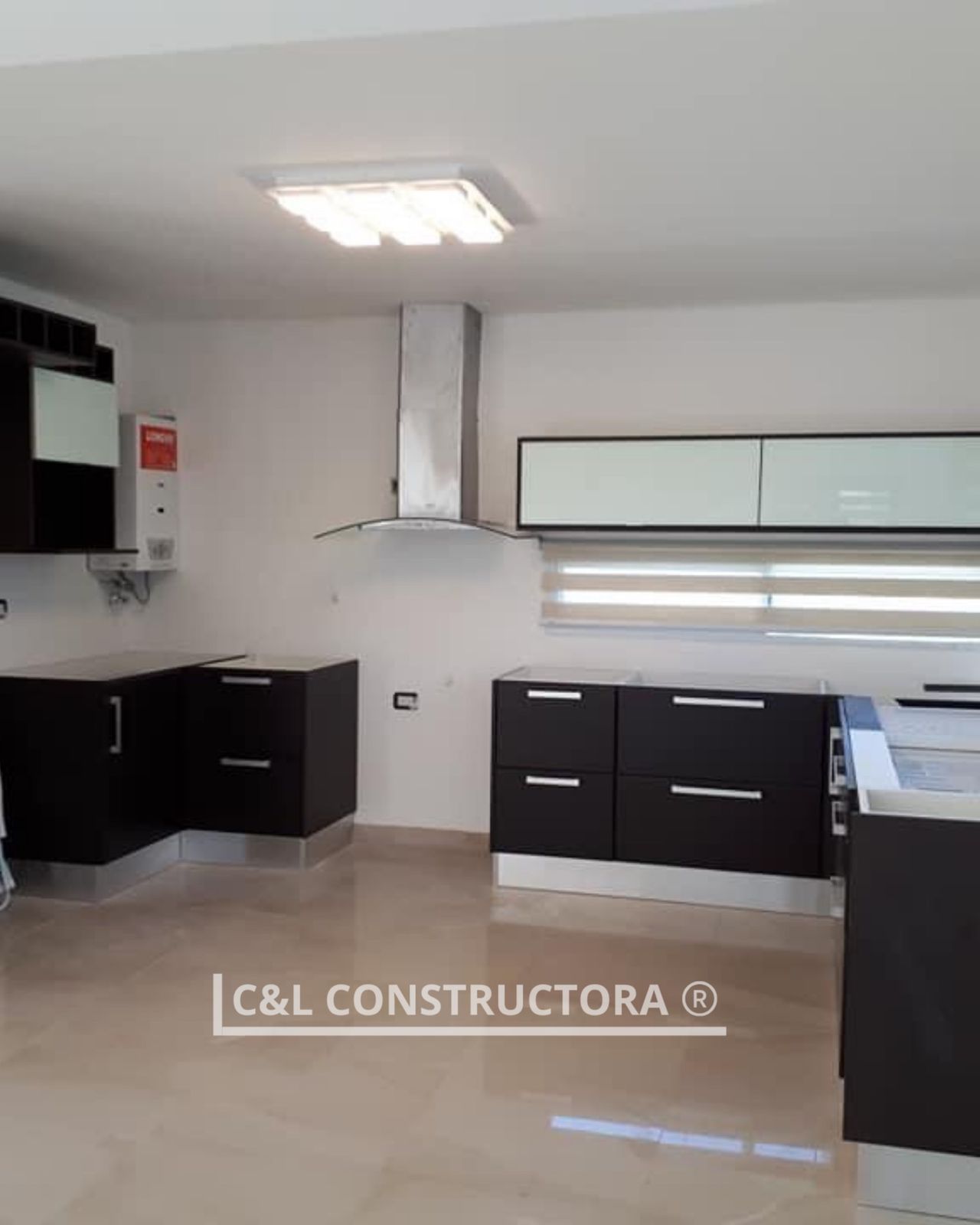 Cocina moderna con gabinetes oscuros, campana extractora de acero inoxidable y pisos de color claro.