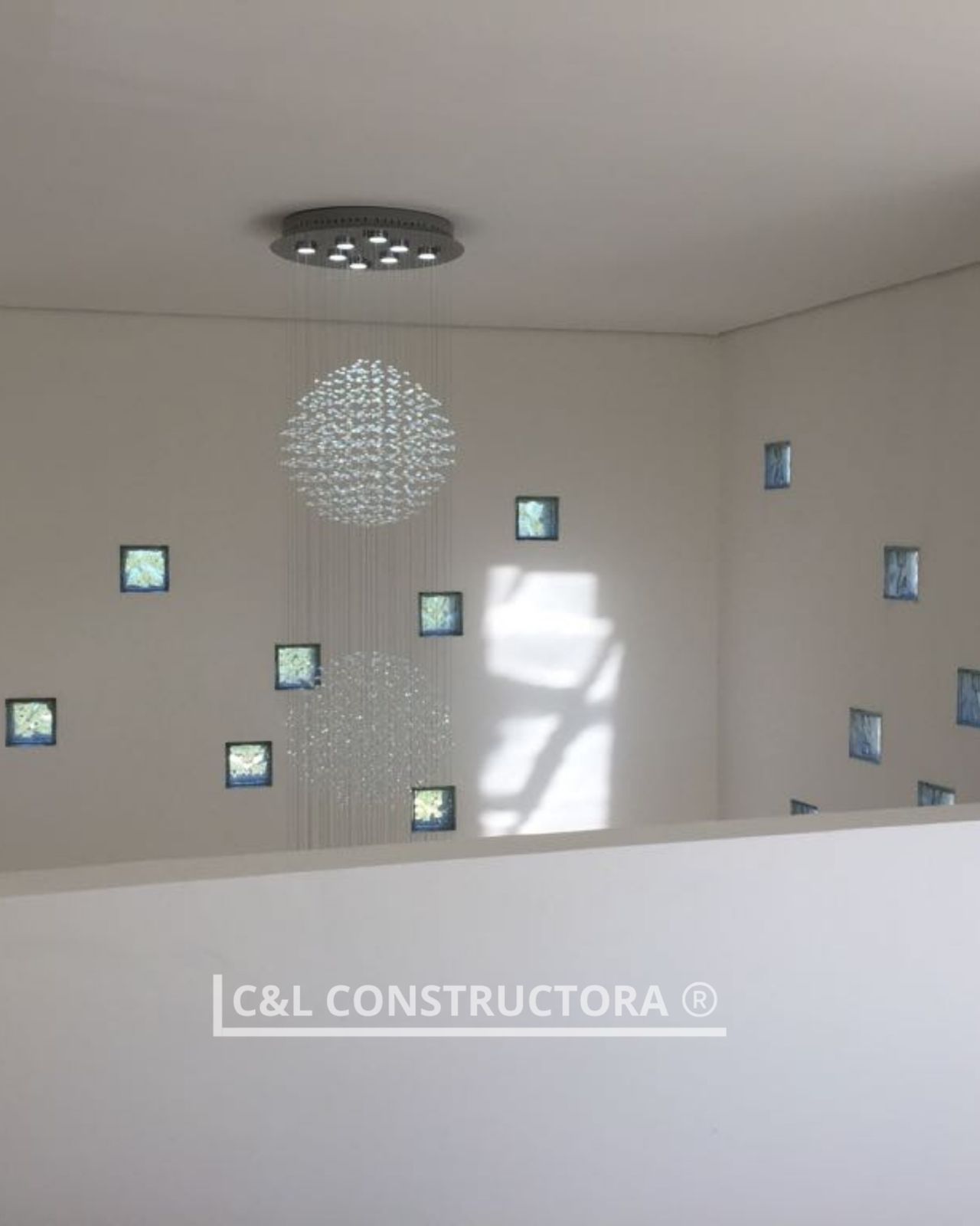 Interior blanco moderno con lámpara de araña con bolas de cristal y ventanas de pared cuadradas.