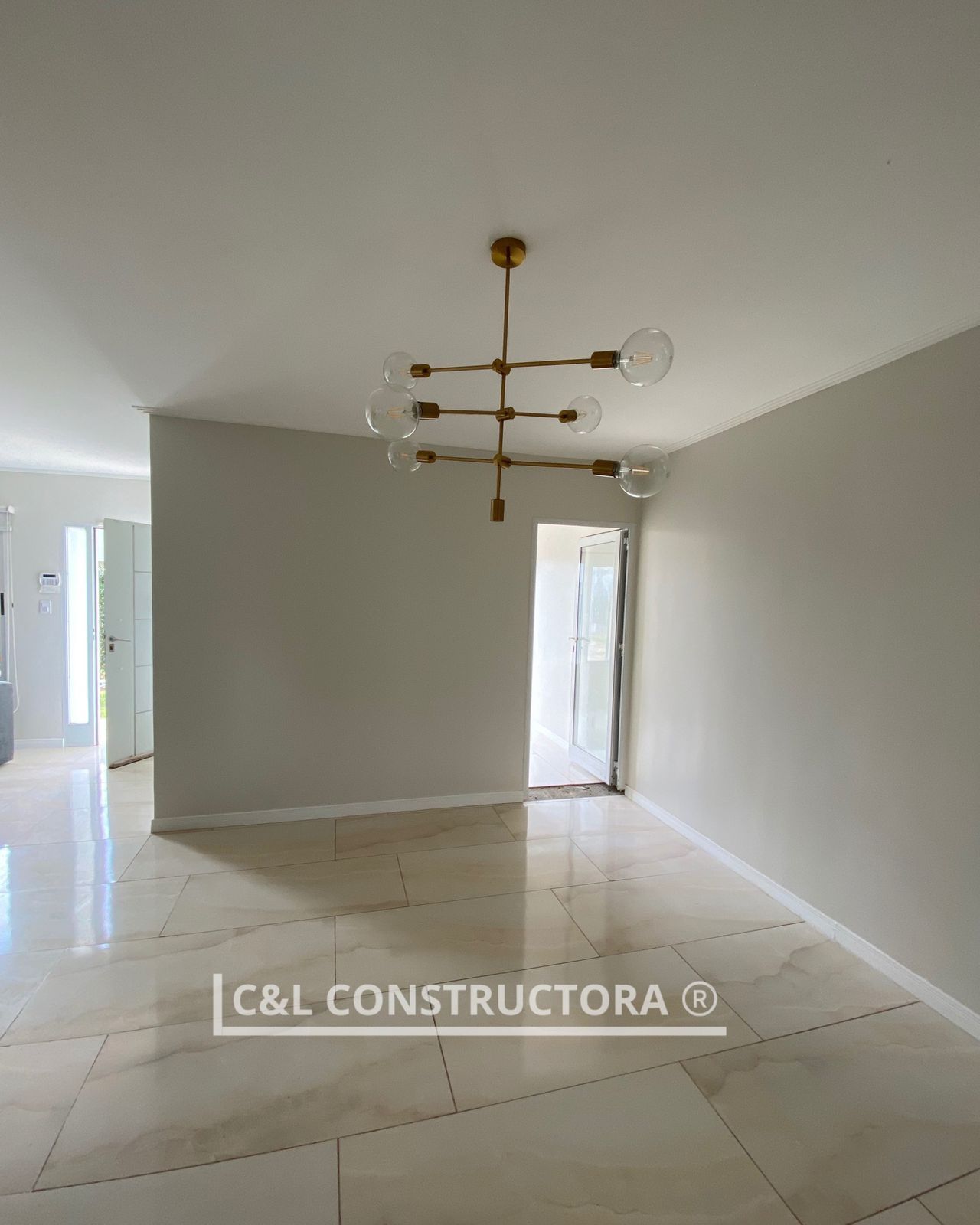 Habitación vacía y luminosa con suelo de baldosas beige y una lámpara de araña moderna