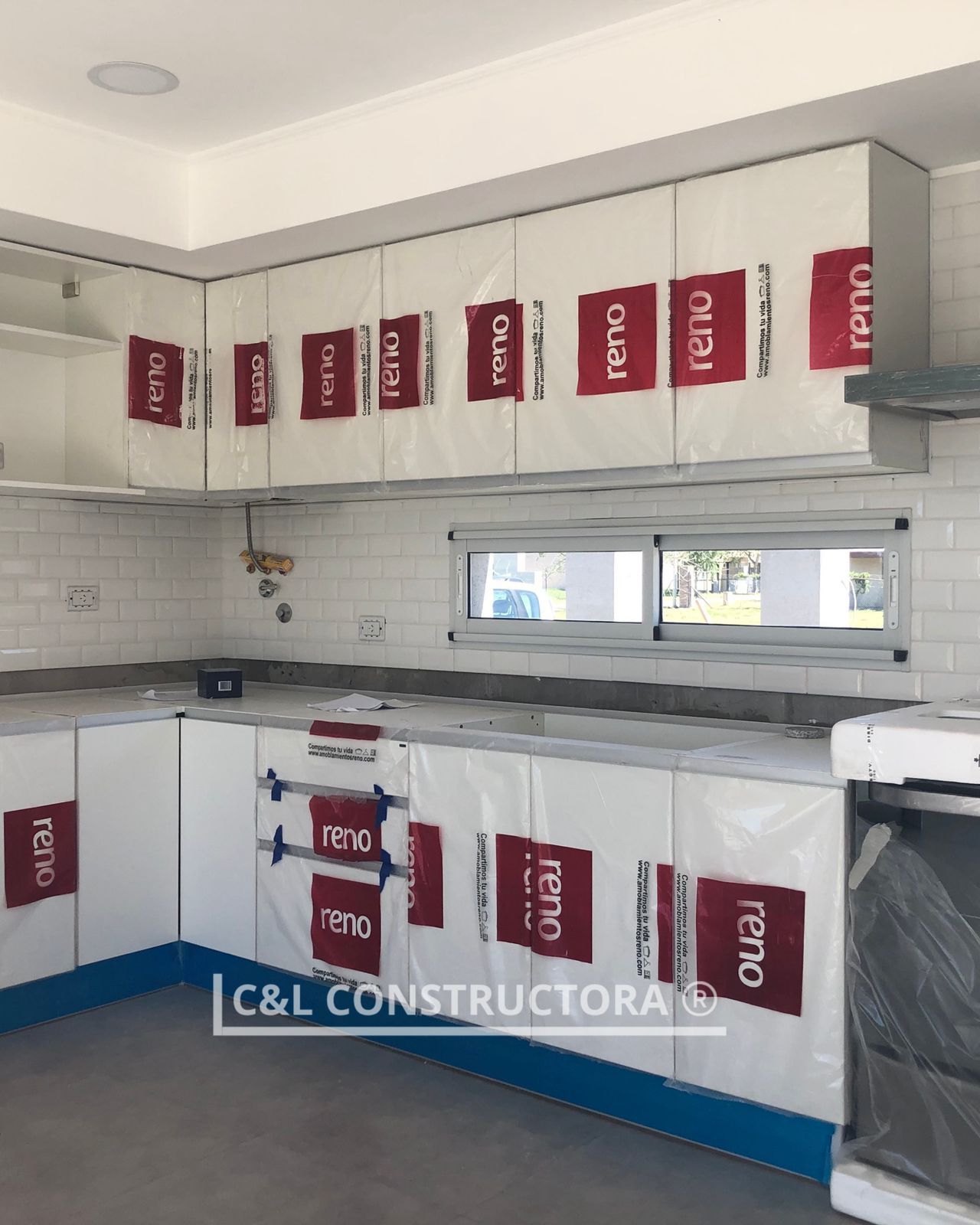 Gabinetes de cocina nuevos envueltos en material protector rojo y blanco, listos para usar.