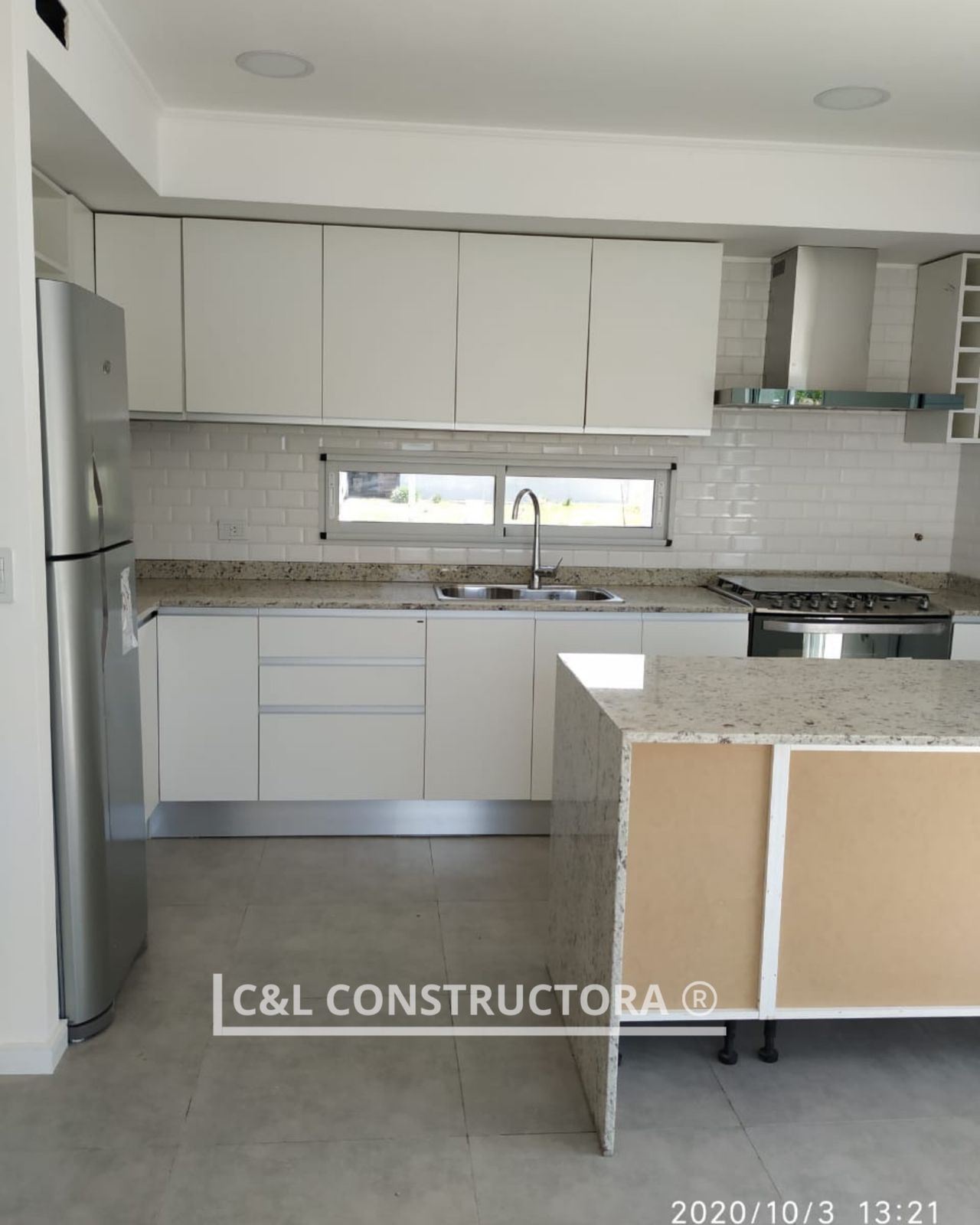 Cocina blanca moderna con electrodomésticos de acero inoxidable y encimeras de granito.