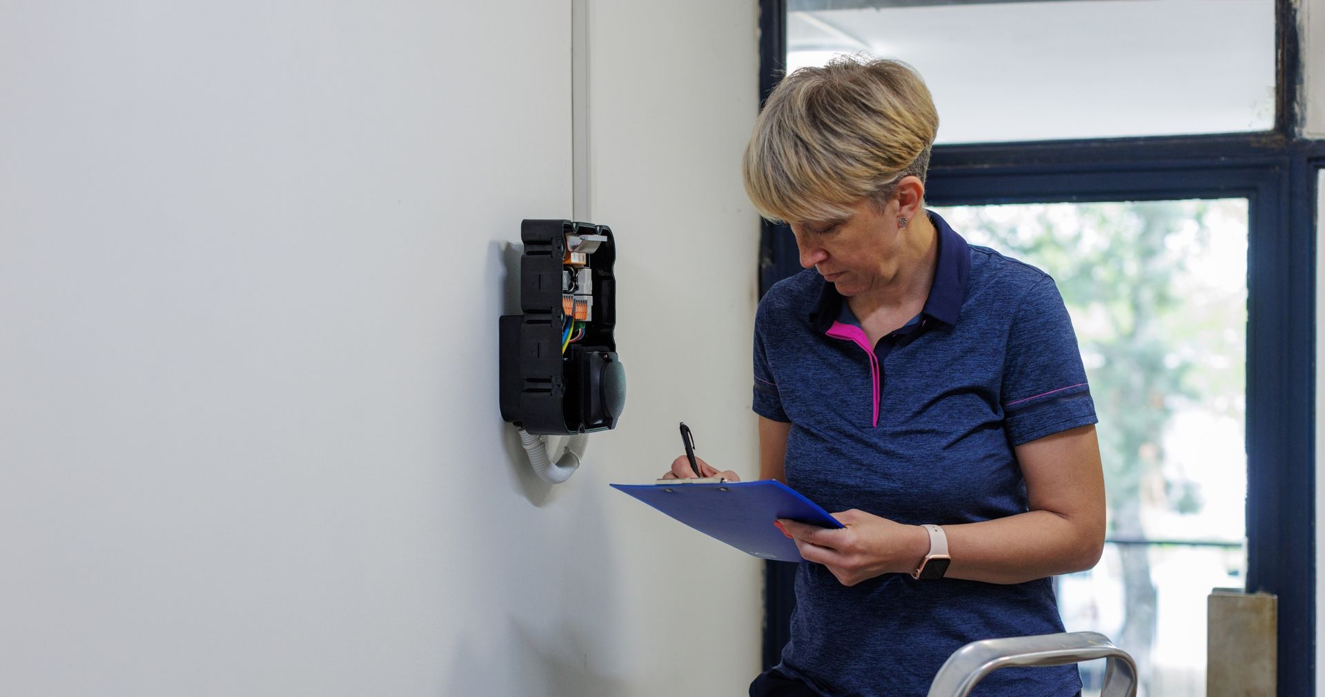A woman is writing on a clipboard in a room.