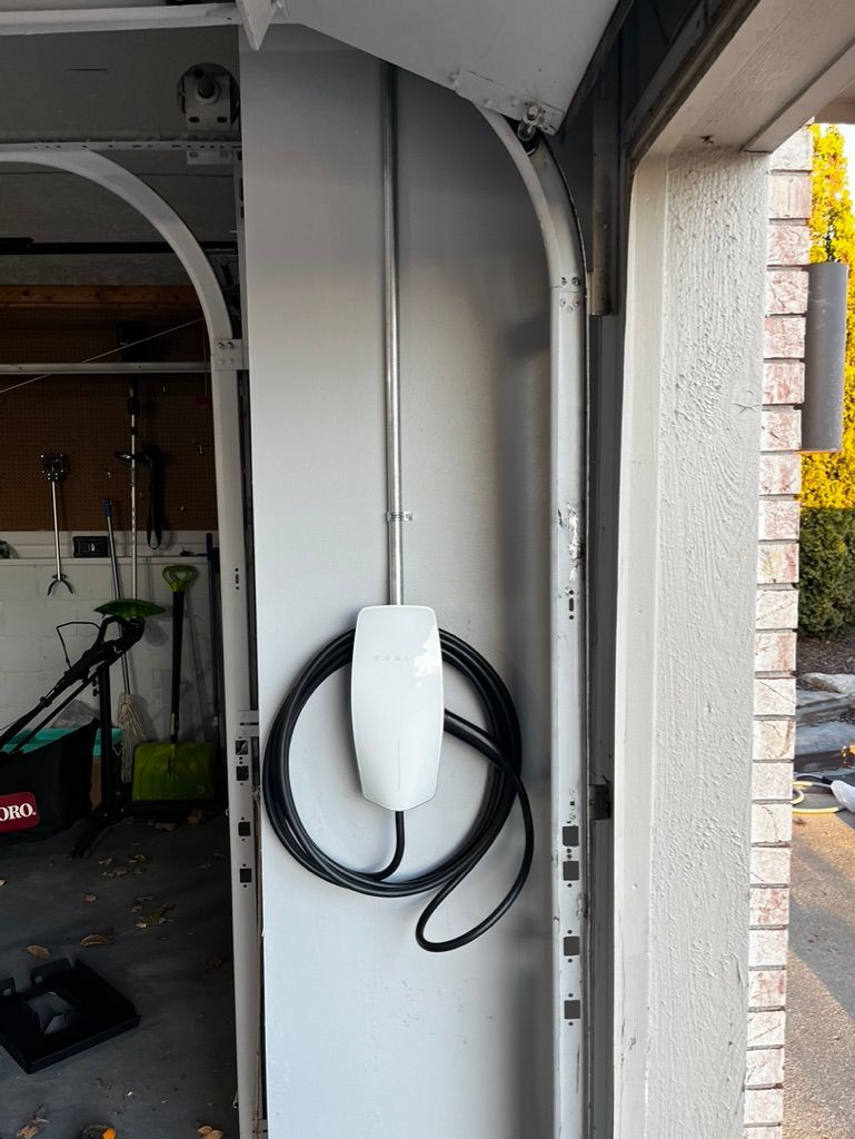 A tesla charging station is attached to the side of a garage door.