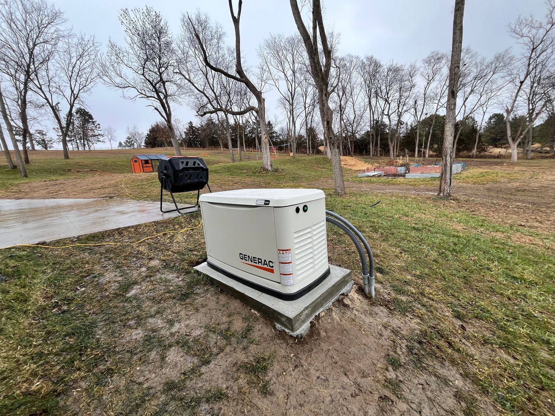 A generator is sitting in the grass next to a grill.