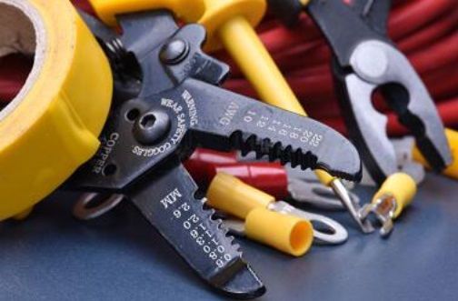 A pair of wire cutters sitting on top of a table next to a roll of yellow tape.