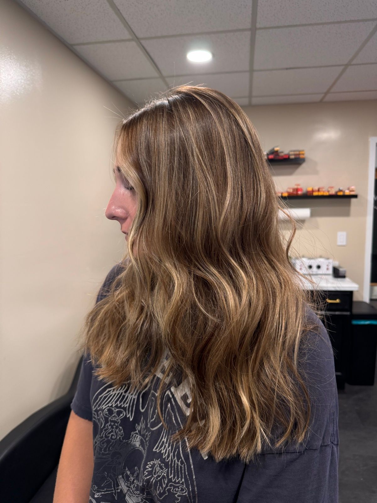 Side view of a person with wavy light-brown hair in an office room.