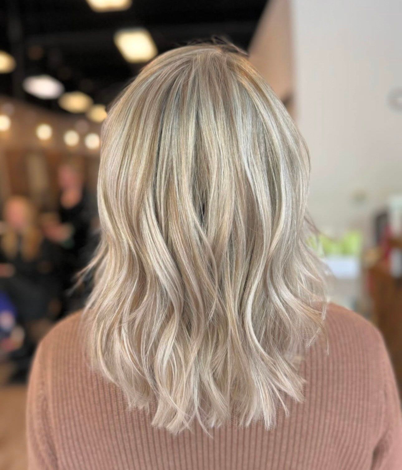 Back view of shoulder-length silver-blonde wavy hair in a salon setting