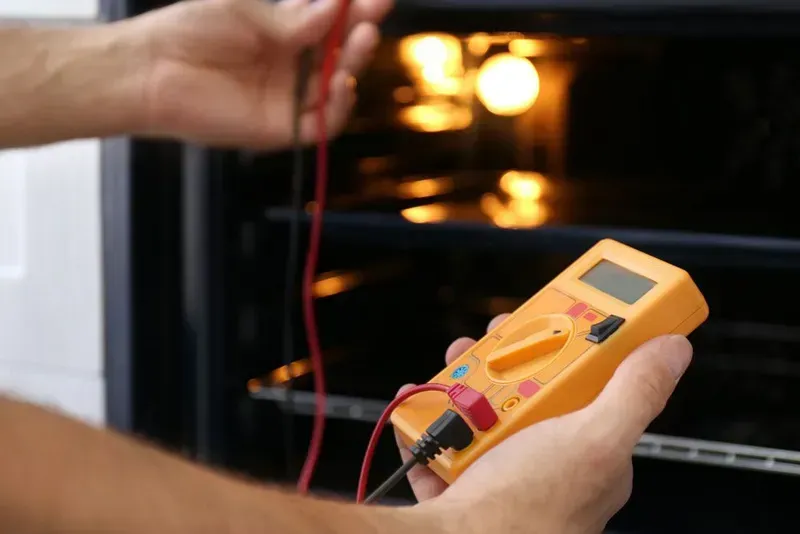 A Person Holding a Yellow Digital Multimeter — CH Electrics in Emerald, QLD