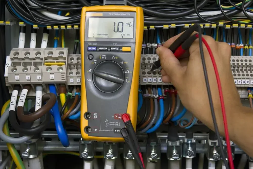 A Technician Uses a Yellow Multimeter to Test Electrical Connections — CH Electrics in Emerald, QLD