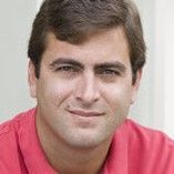 A man in a red shirt is smiling for the camera.