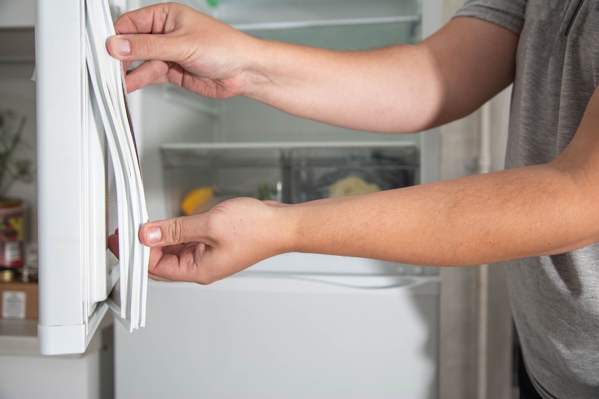 A man is opening the door of a refrigerator. A man is opening the door of a refrigerator.
