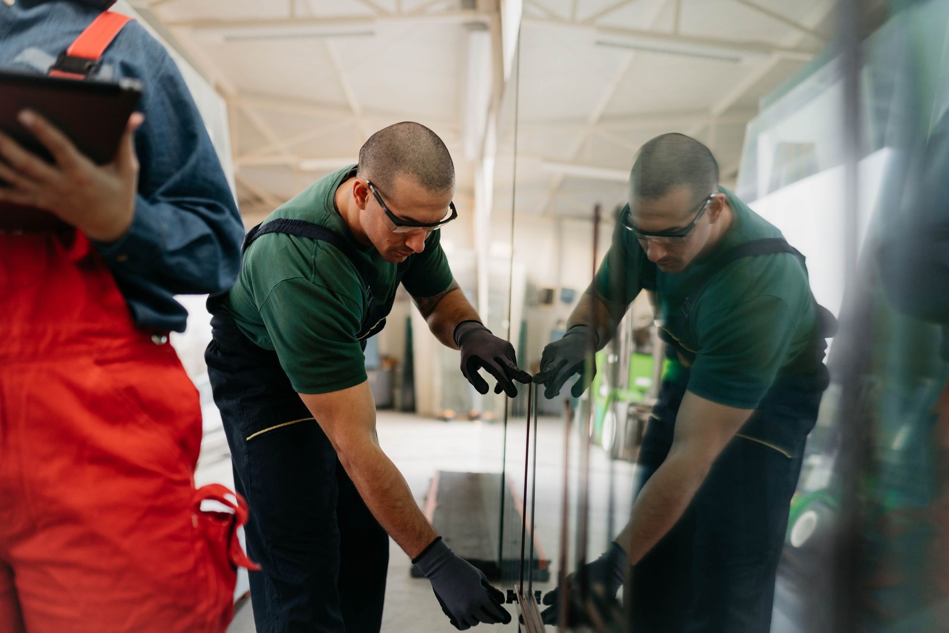 Two men are working on a piece of glass in a factory.