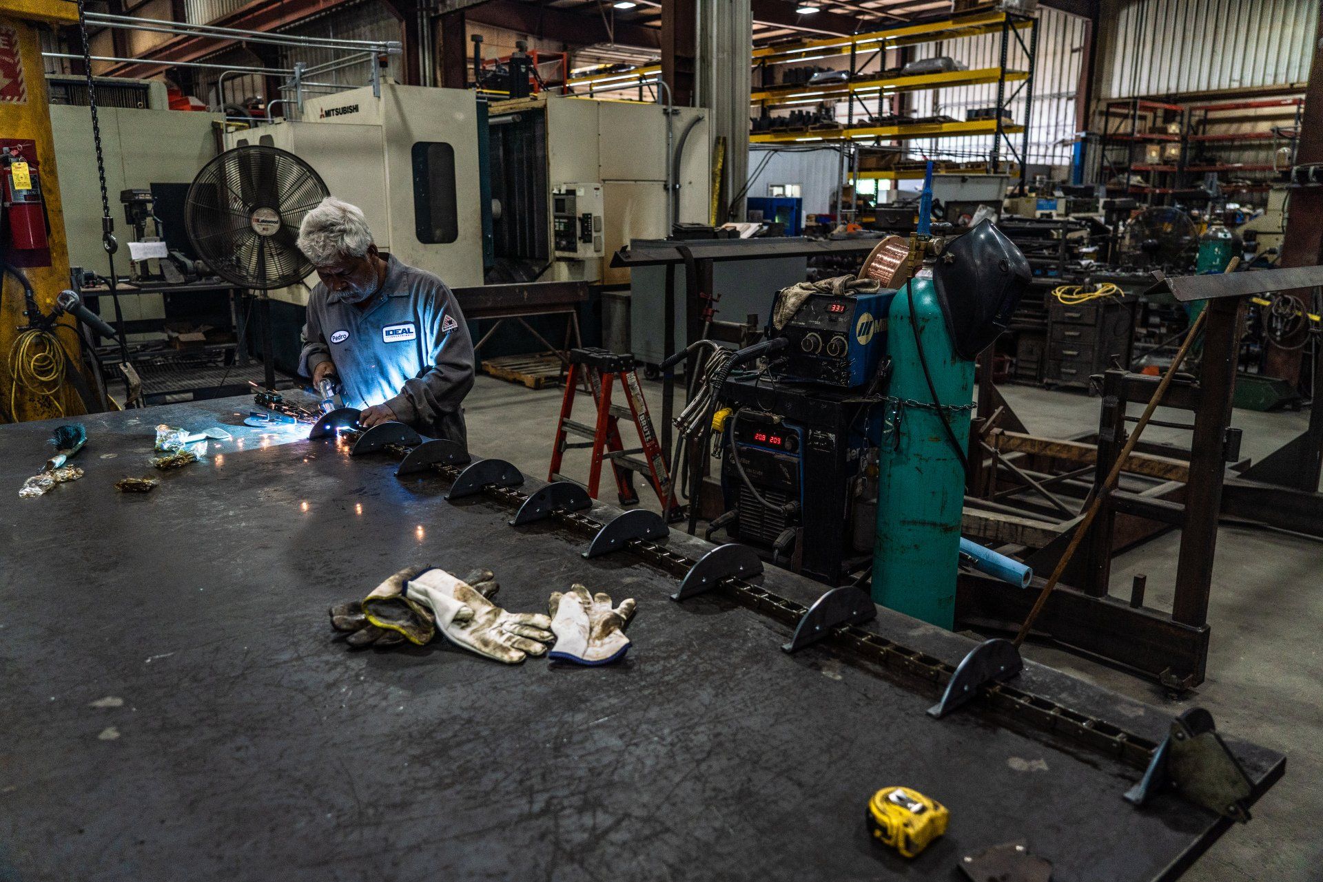 A man is welding a piece of metal in a factory.