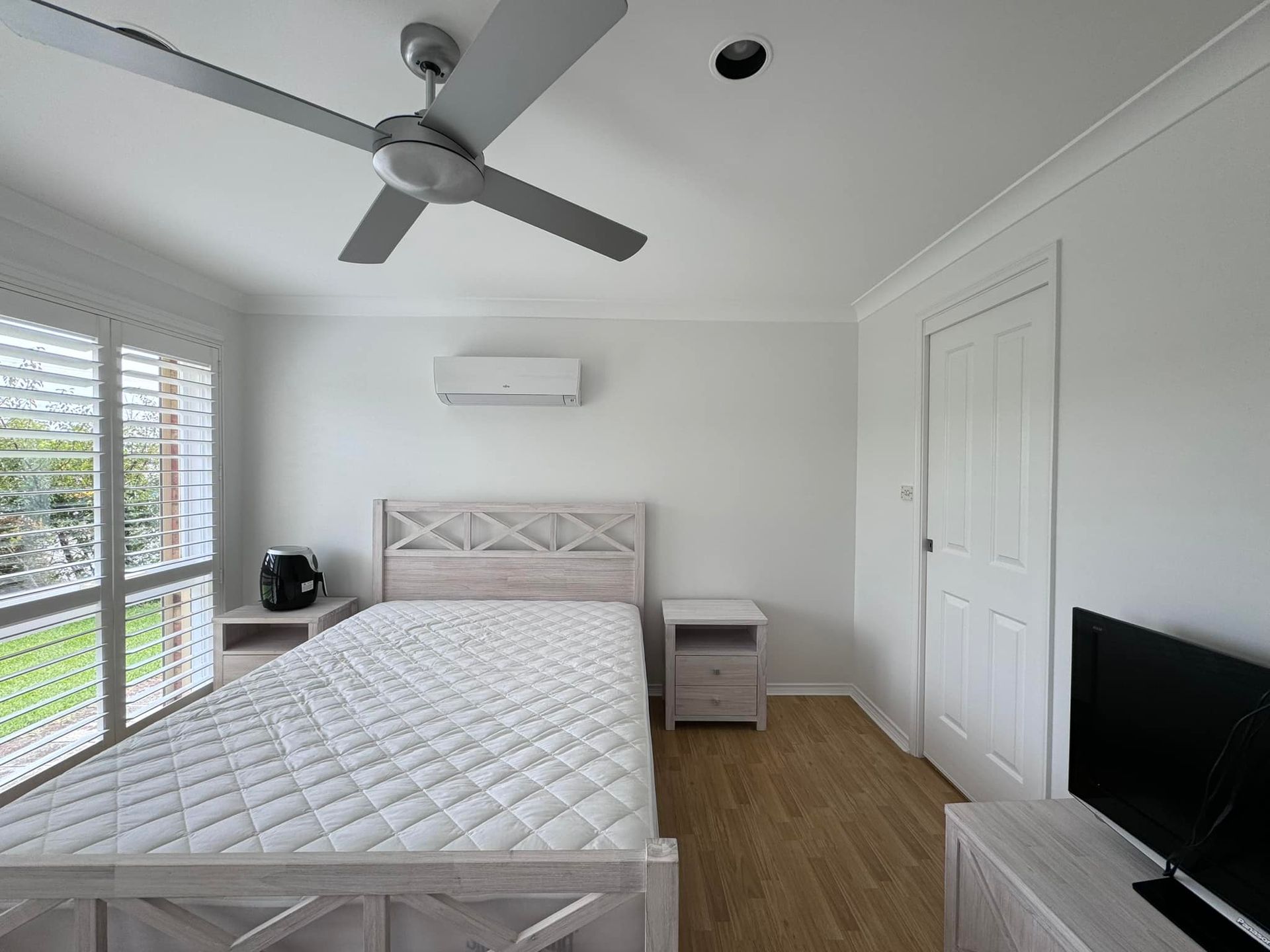 Bedroom with a bed, two nightstands, a television, and a ceiling fan.  — JAX Painting Services in Central Coast, NSW