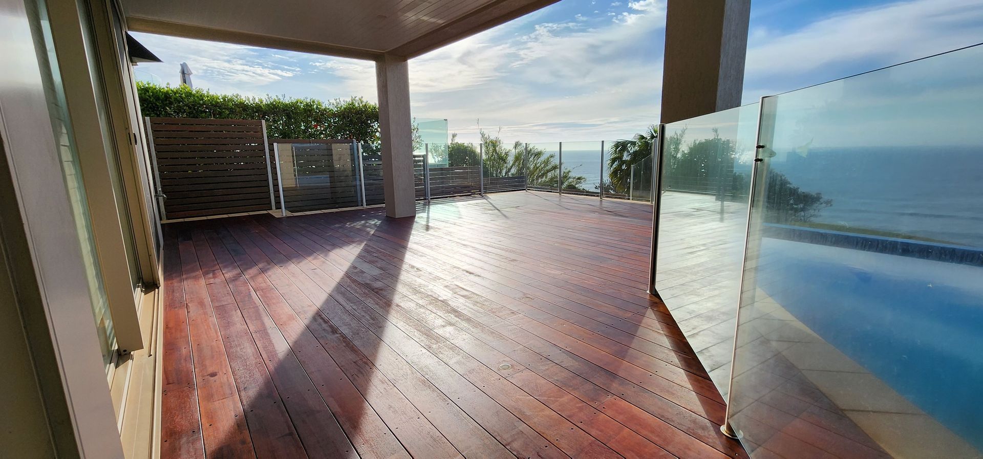 A Wooden Deck With a Glass Railing Overlooking the Ocean — JAX Painting Services in Central Coast, NSW