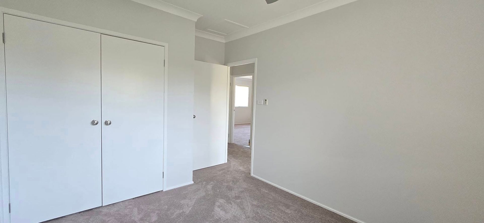 An Empty Bedroom With a Carpeted Floor and White Walls — JAX Painting Services in Central Coast, NSW