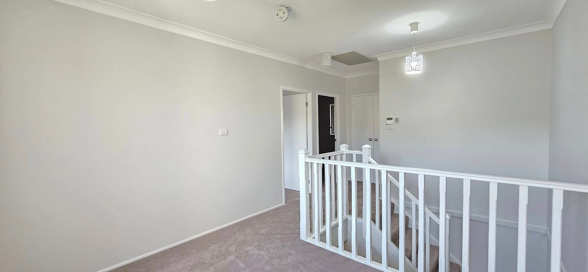 An Empty Room With a Staircase and a White Railing — JAX Painting Services in Central Coast, NSW