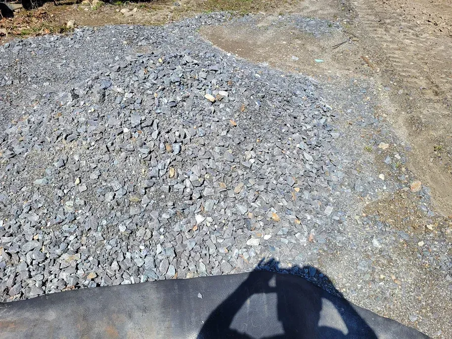A pile of crushed grey gravel sits on the ground, with a partial shadow cast over the foreground.