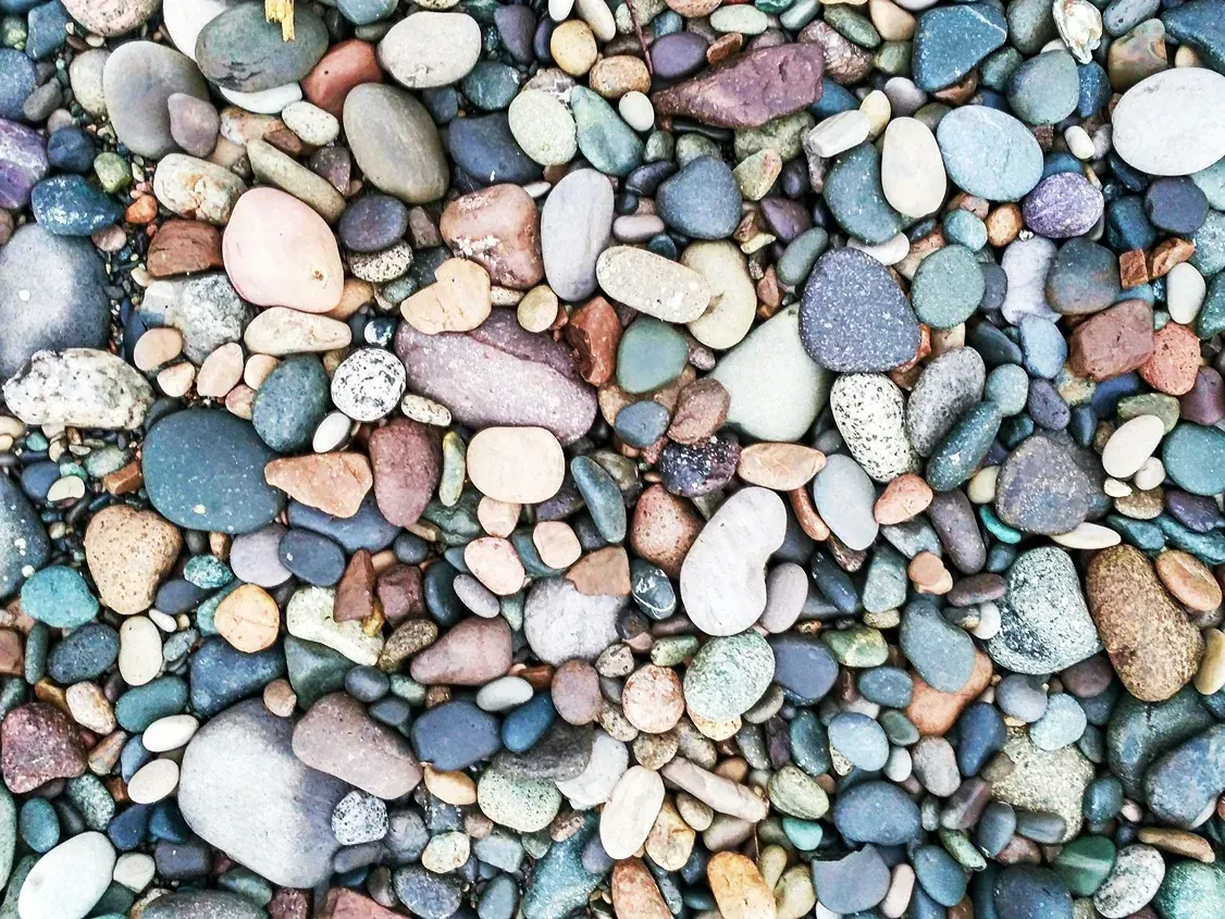 A collection of smooth, multi-colored pebbles and stones of various shapes and sizes covering the ground.