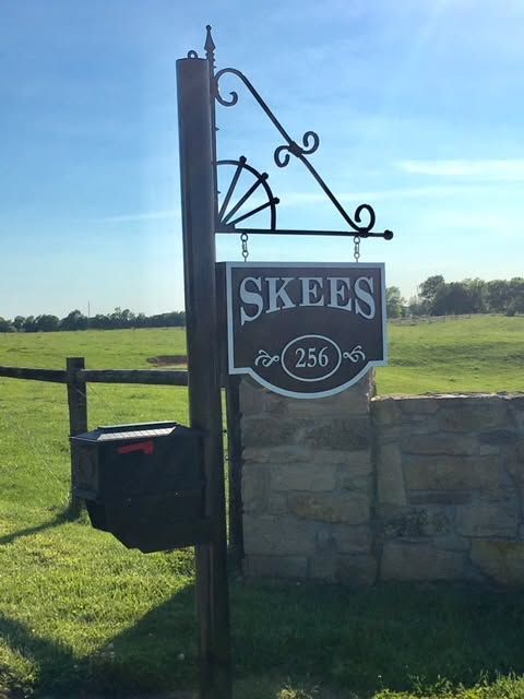 Stone entrance sign reading “SKEES” with number 256 beside a black mailbox in a grassy field. Stone entrance sign reading “SKEES” with number 256 beside a black mailbox in a grassy field.