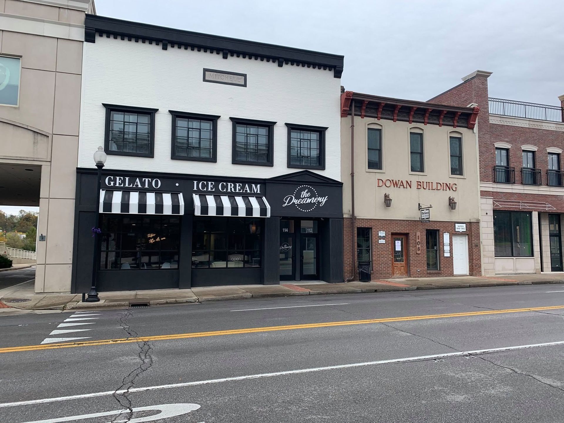 Street view of a row of storefronts, including a black-and-white gelato shop and neighboring businesses. Street view of a row of storefronts, including a black-and-white gelato shop and neighboring businesses.