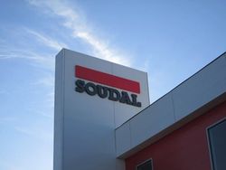 Soudal logo on a white building against a blue sky.