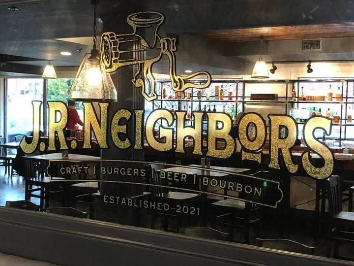 J.R. Neighbors bar logo on glass window with gold lettering and bourbon-themed graphics. J.R. Neighbors bar logo on glass window with gold lettering and bourbon-themed graphics.