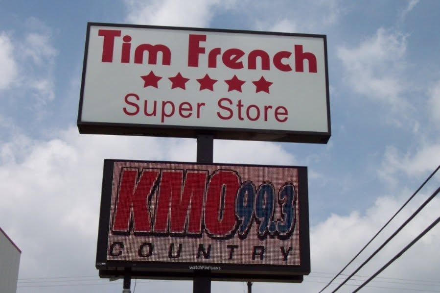 Signs for Tim French Super Store and KMOX 1120 Country against a cloudy sky. Signs for Tim French Super Store and KMOX 1120 Country against a cloudy sky.