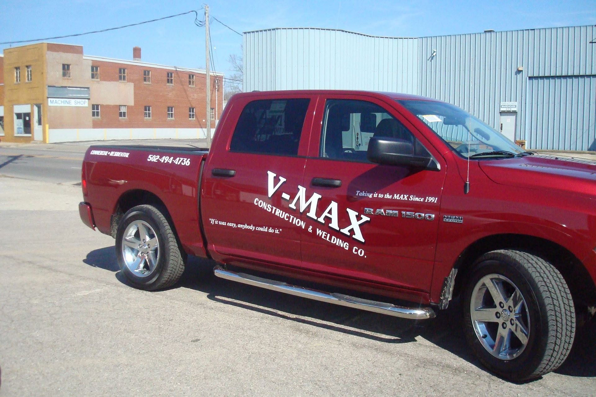 Red V-MAX pickup truck parked outdoors beside a metal building. Red V-MAX pickup truck parked outdoors beside a metal building.
