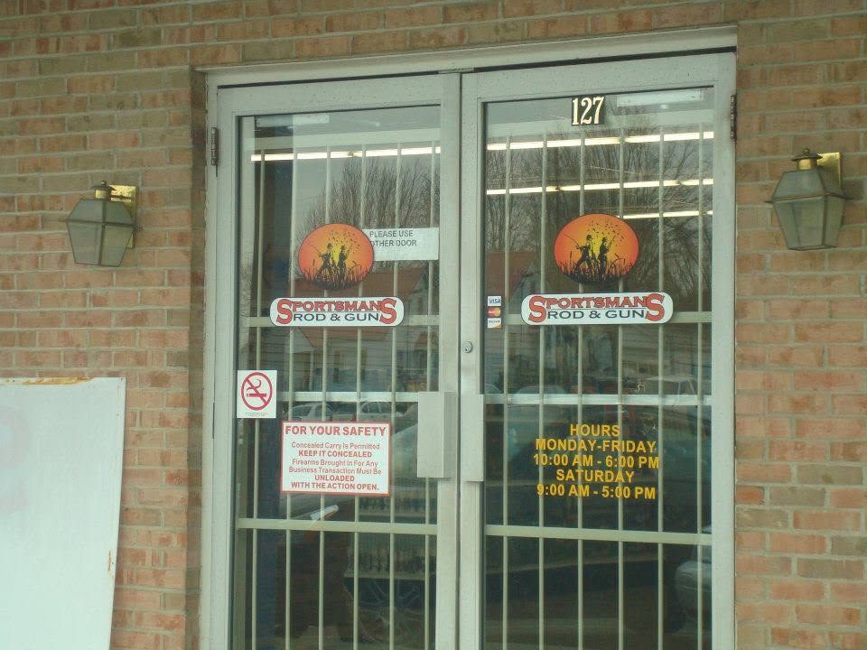 Brick storefront entrance with double glass doors, signs, and black metal security bars. Brick storefront entrance with double glass doors, signs, and black metal security bars.