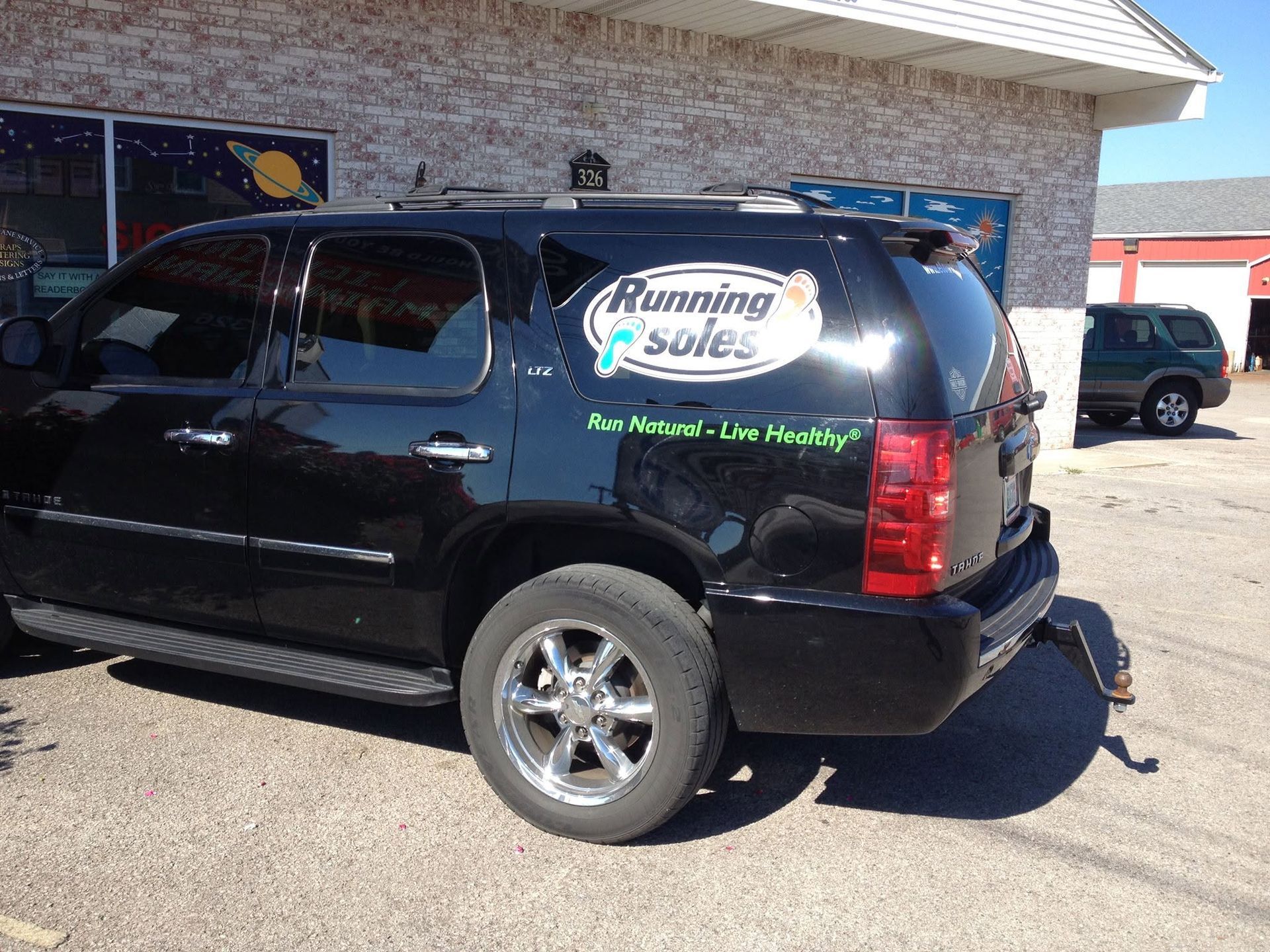 Black SUV with business decals parked beside a building on a sunny day. Black SUV with business decals parked beside a building on a sunny day.