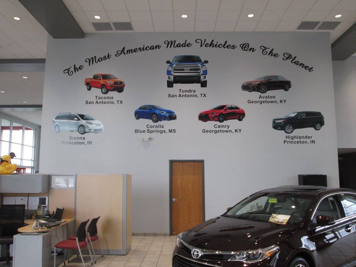 Car showroom with a mural of classic cars on the wall and a black SUV in the foreground. Car showroom with a mural of classic cars on the wall and a black SUV in the foreground.