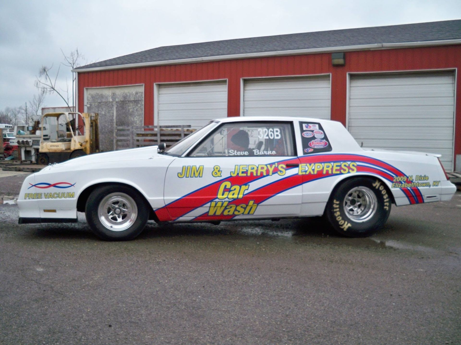 White drag racing car with colorful graphics parked in front of garage doors. White drag racing car with colorful graphics parked in front of garage doors.