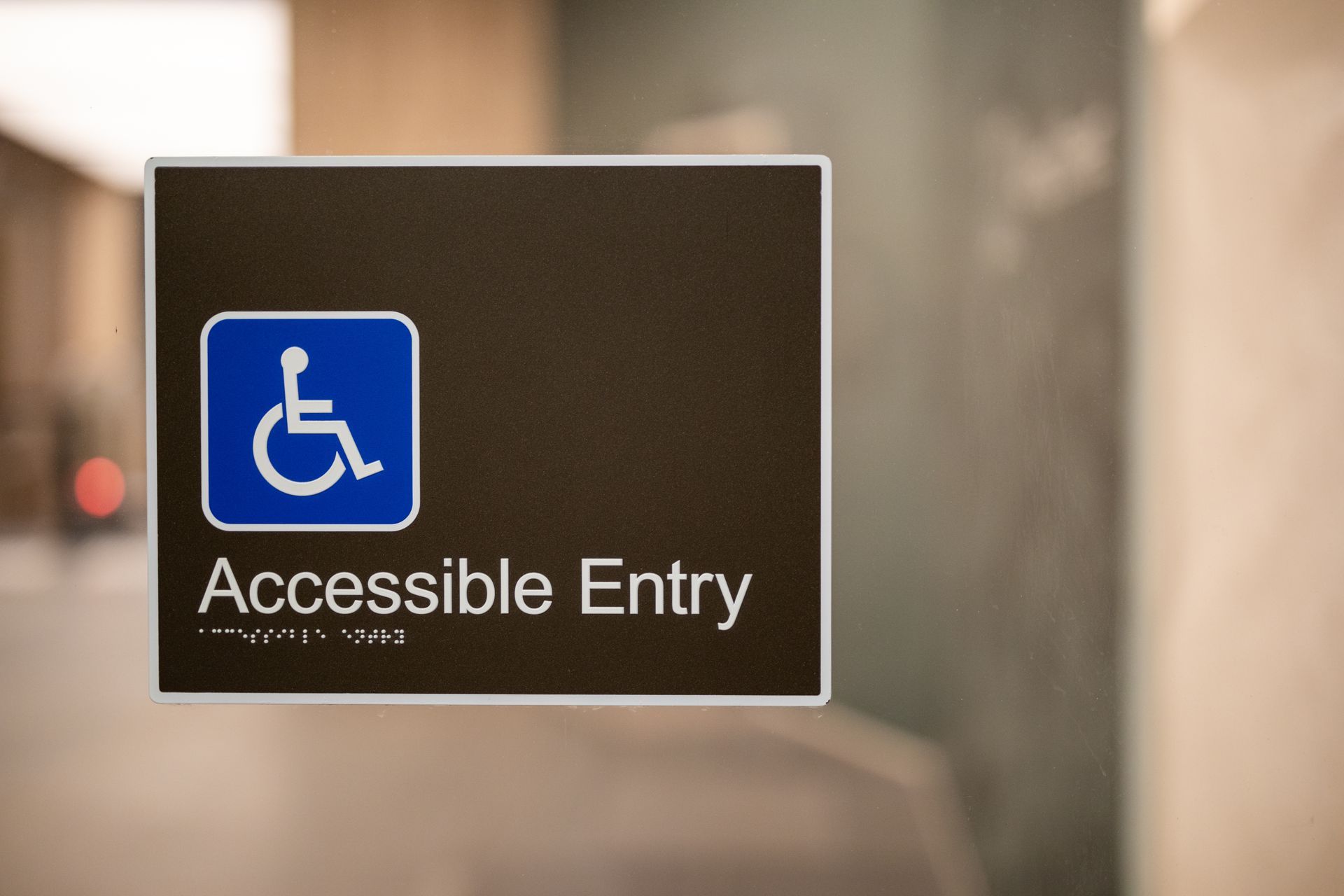 Blue wheelchair symbol sign reading “Accessible Entry” on a glass door. Blue wheelchair symbol sign reading “Accessible Entry” on a glass door.
