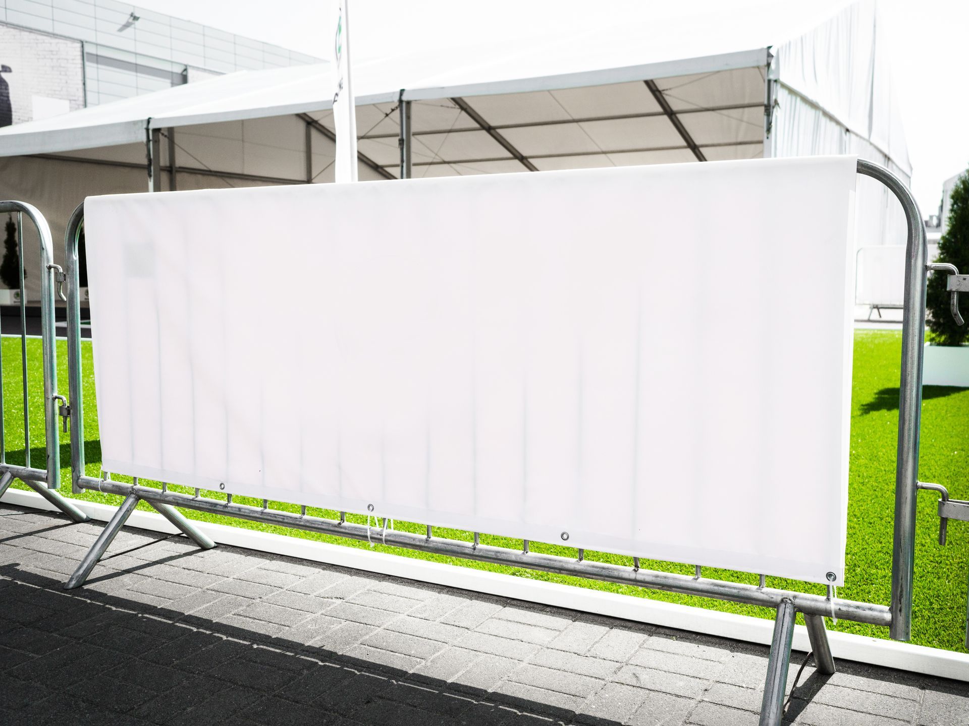 Blank white custom banners vinyl mounted on a metal barricade frame at an outdoor event.