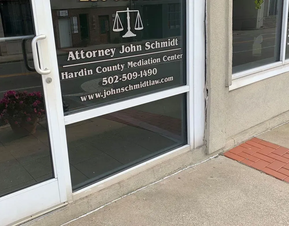 Law office glass door with sign for Attorney John Schmidt and Hardin County Mediation Center.
