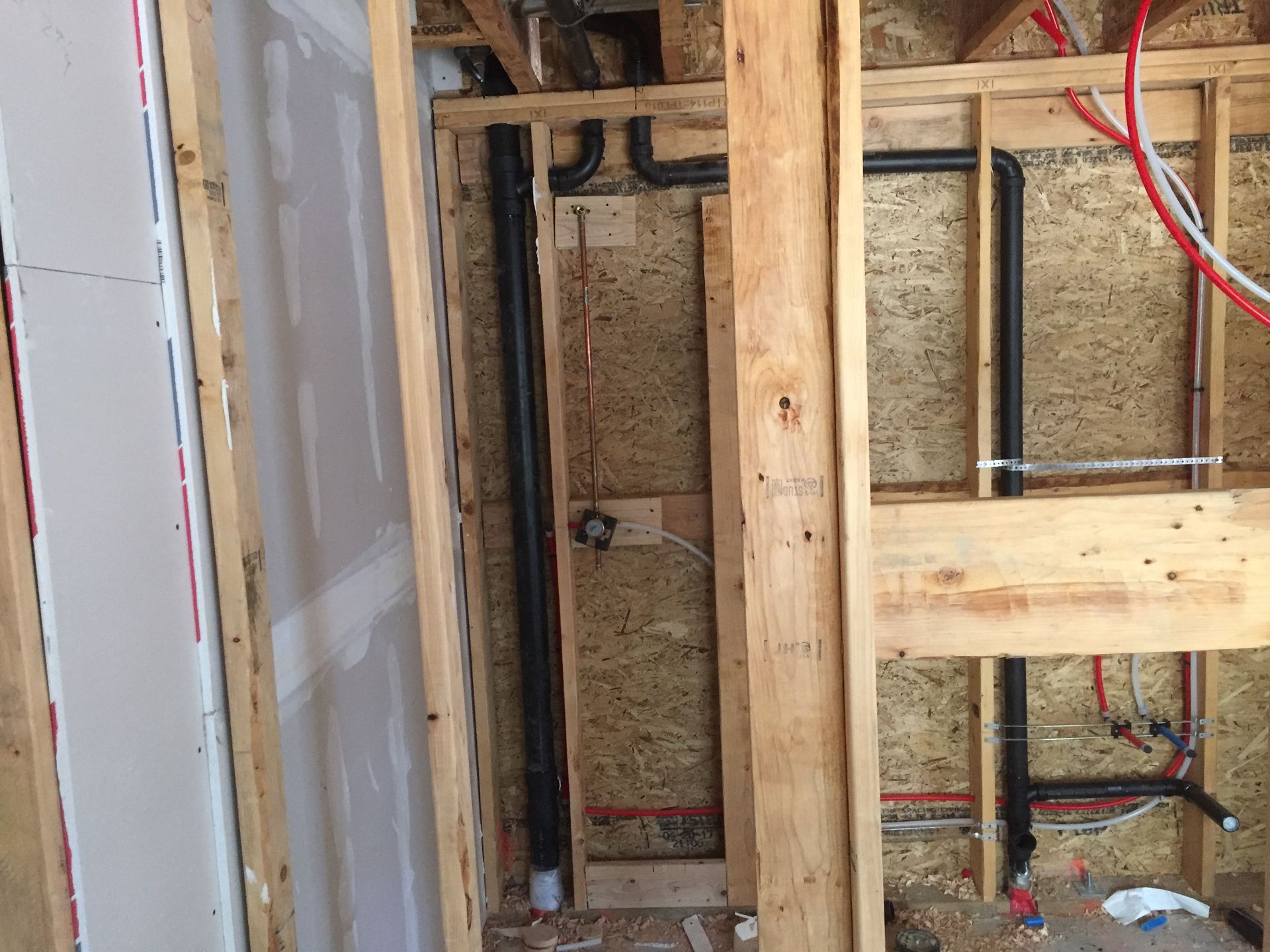 A wooden wall with pipes and wires coming out of it