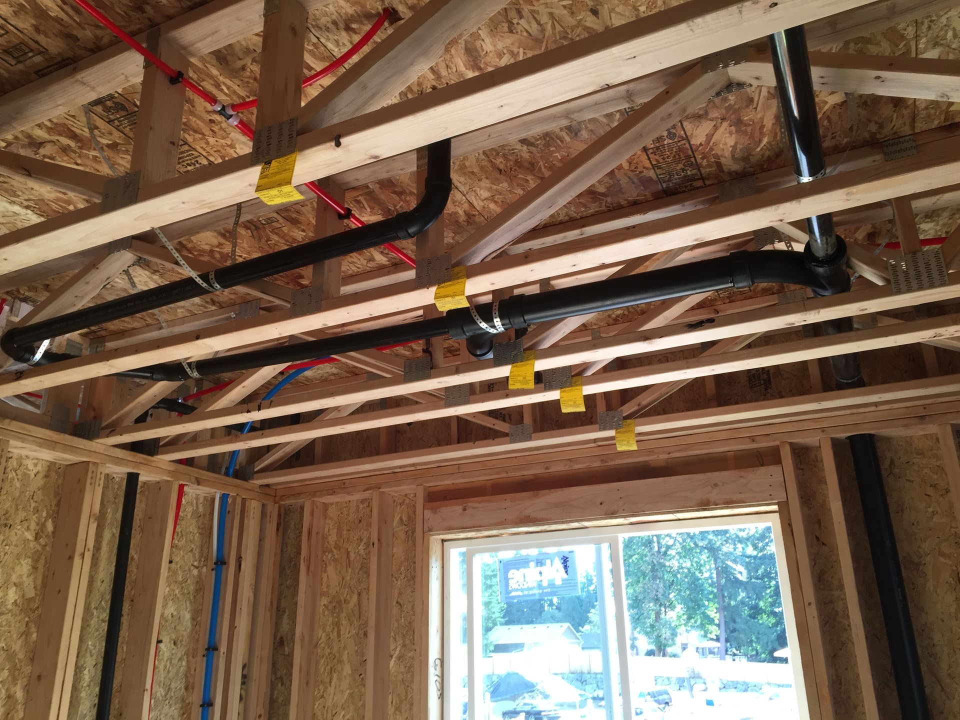 A room with a window and pipes hanging from the ceiling