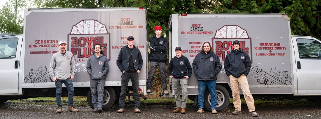 A group of men are standing in front of two trucks.
