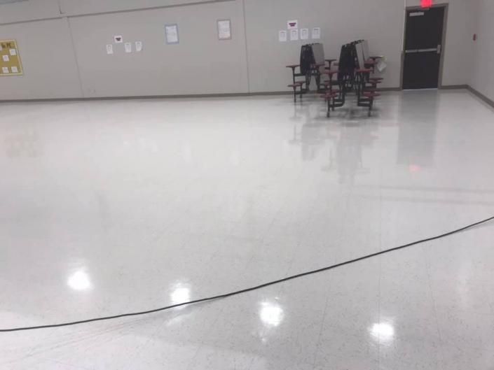 Empty glossy room with stacked chairs near a door and a long cable across the floor