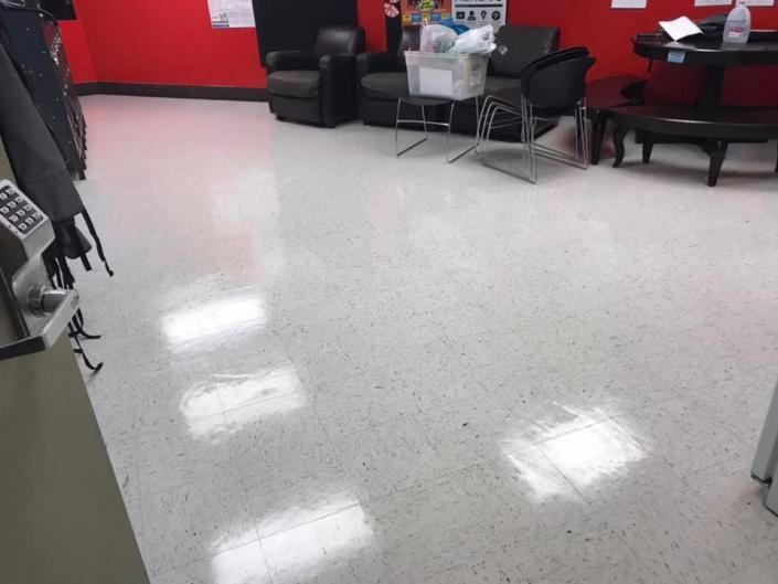 Empty showroom floor with red walls, black chairs, and a small glass table.