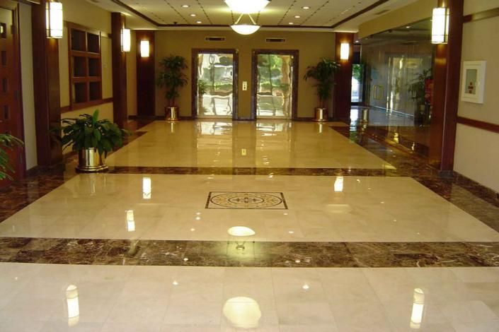 Empty hotel lobby with polished marble floor and glass entrance doors