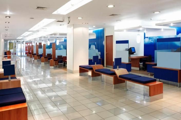 Bright modern lounge with blue and wood benches, tiled floor, and white columns in a spacious indoor area